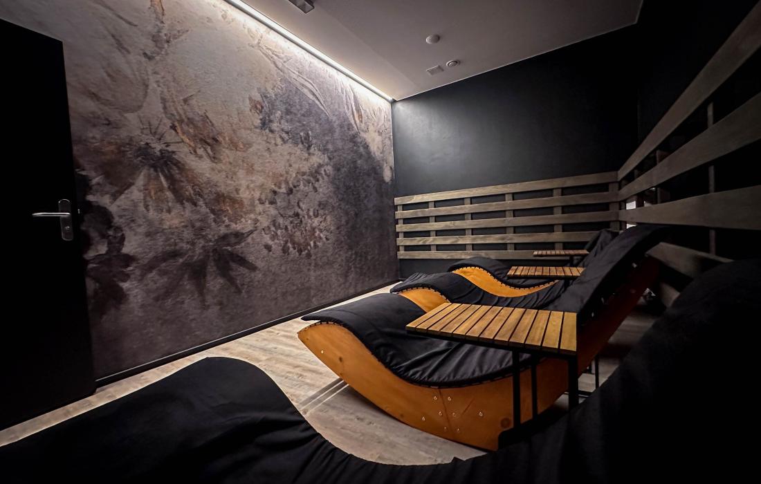 Wnętrze pomieszczenia do odpoczynku po sesji saunowania. Leżaki w ciemnym pokoju z artystyczną fototapetą.