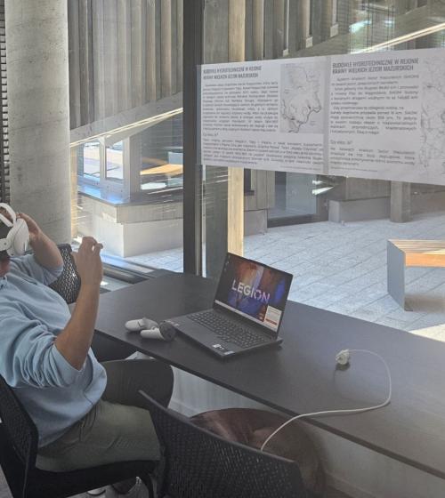 Pracownik portu siedzi przy biurku z założonym zestawem googli VR z aplikacją do szkoleń żeglarskich. 